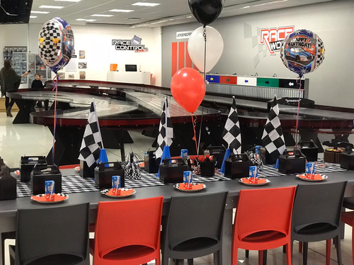 The picture shows the race track and an example of a race car party set up.  There are ballons and checkered flags and slot car racing.